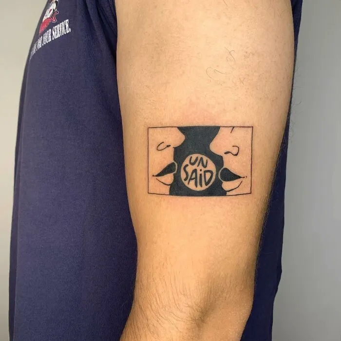 Tattoo resembling an illustration on an arm, depicting two faces with "UN SAID" in the center.