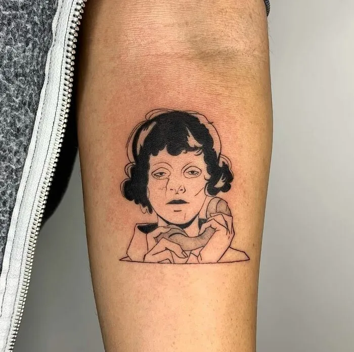 Illustration-style tattoo of a woman's face and hands on an arm.
