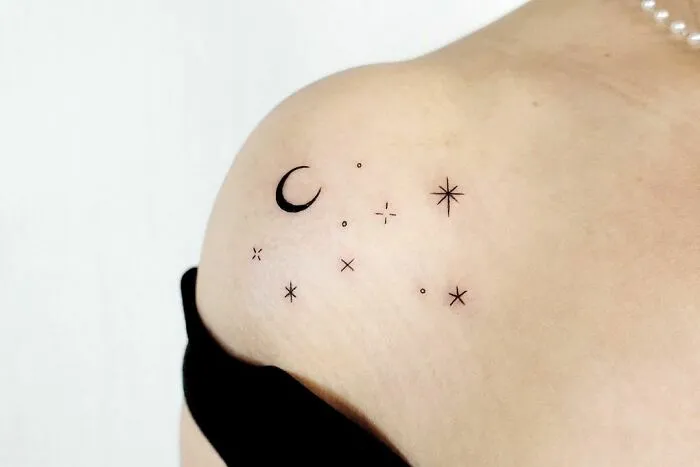 Minimalist space tattoo with stars and crescent moon on shoulder, perfect for astrology fans.