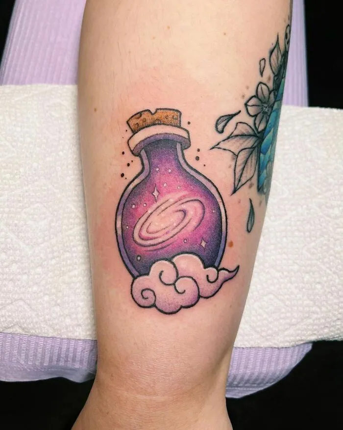 Tattoo of a galaxy in a potion bottle on forearm, representing outer space cool theme.