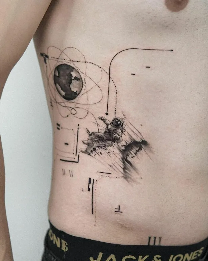 Astronaut tattoo on a person's side with space-themed symbols, reflecting outer space cool design.