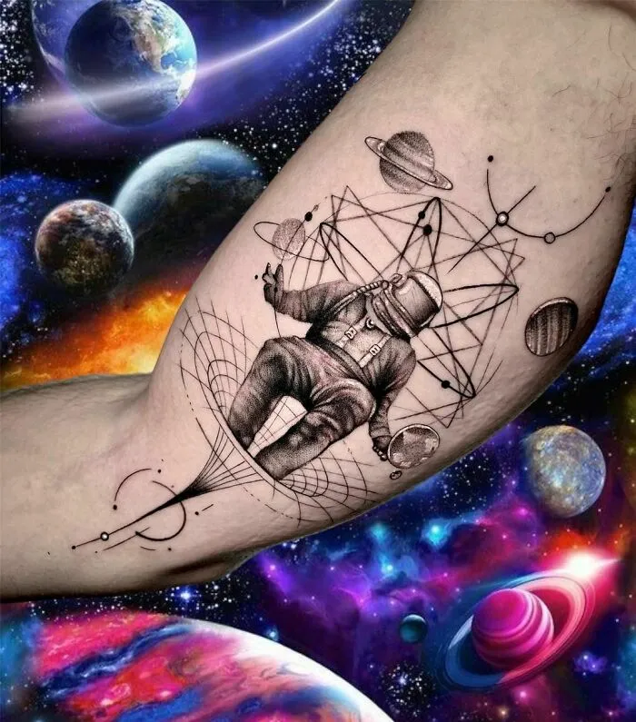 Astronaut tattoo with planets and geometric patterns, showcasing outer space cool.