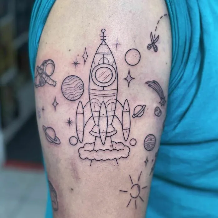 Rocket space tattoo with planets and stars on upper arm for astrology fans.