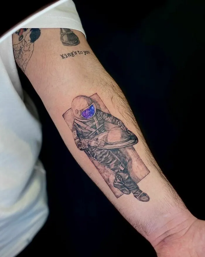 Astronaut tattoo on arm, showcasing outer space cool design details.