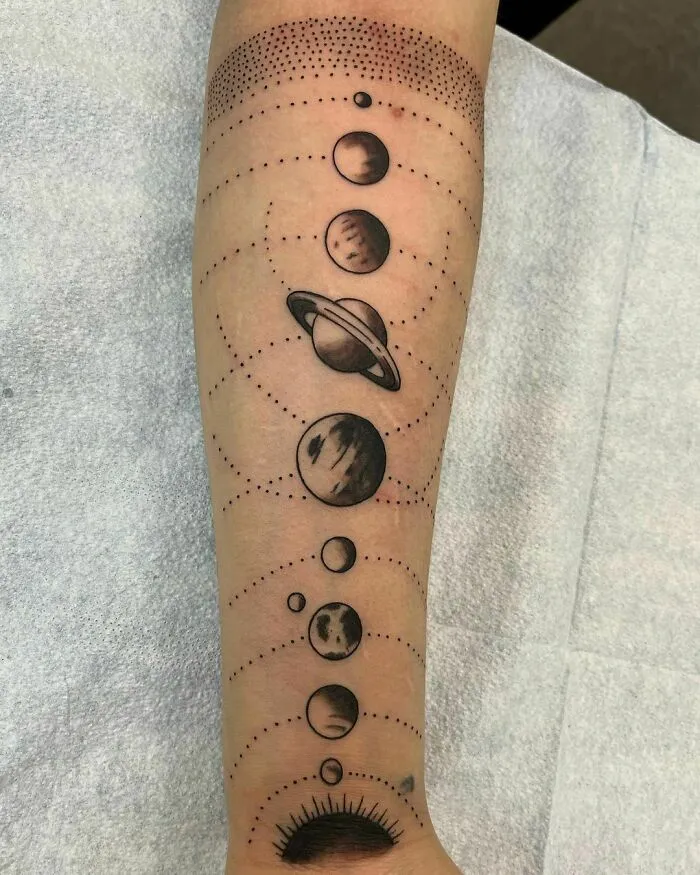 Space tattoo featuring planets in a solar system design on an arm.