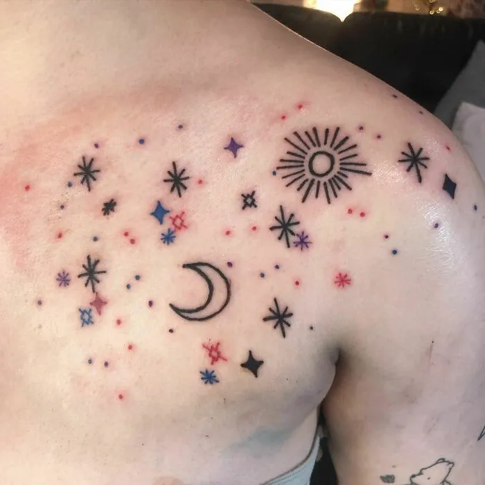 Astrology-themed space tattoos featuring stars, moon, and sun on a person's shoulder.