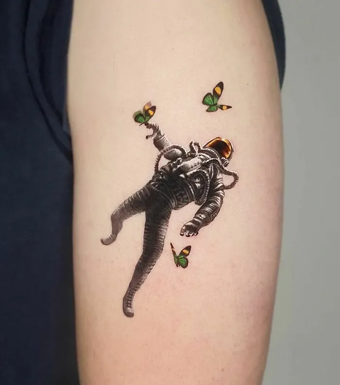 Astronaut tattoo with butterflies, showcasing cool outer space design on an arm.