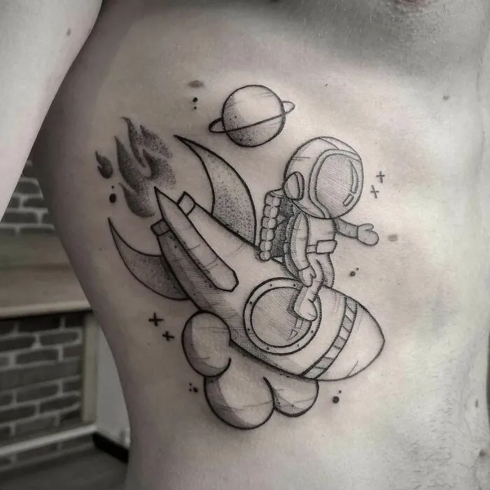 Space tattoo featuring an astronaut on a rocket with planets in the background.