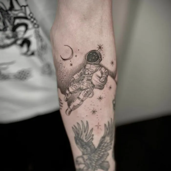 Space tattoo of an astronaut and stars on forearm for astrology fans.