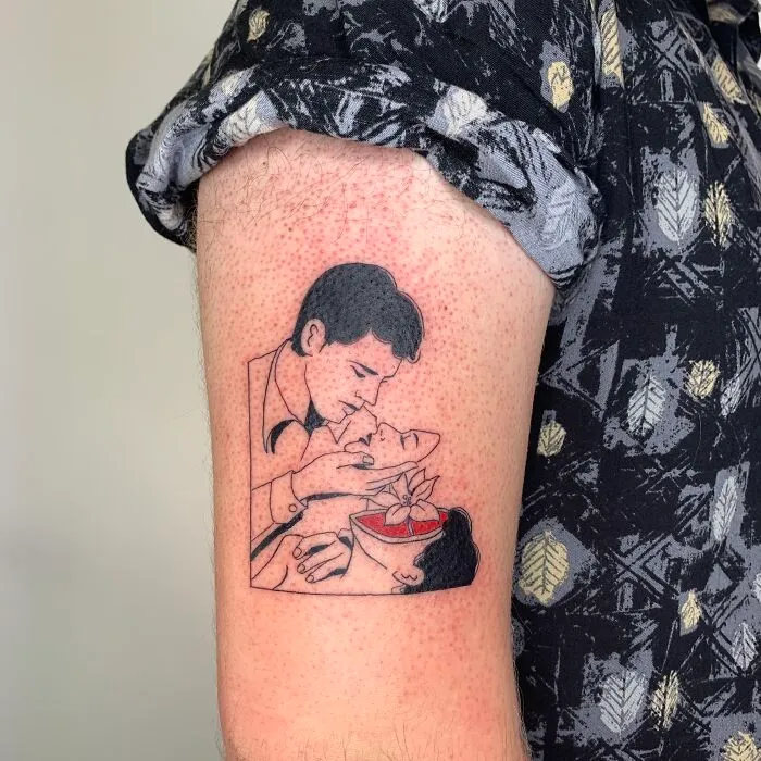 Tattoo artist creates an illustration-style tattoo on a person's upper arm, depicting a vintage romance scene.