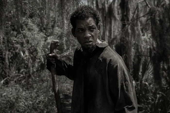 Actor in rugged clothing holding a wooden staff in a forest scene, representing highest-paid actors.