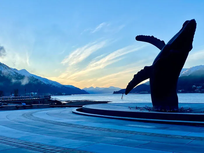A statue of a whale in front of a body of water