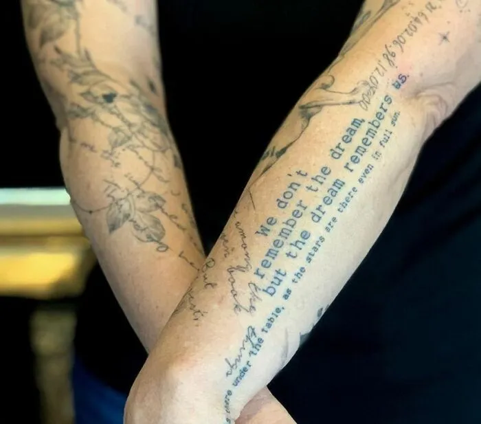 Person with word tattoos on forearms, text includes a dream-related quote, showcasing meaningful ink.