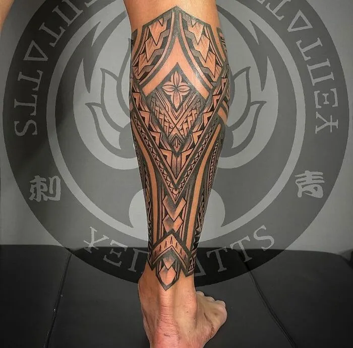 Geometric lower leg tattoo with intricate tribal design in black ink.
