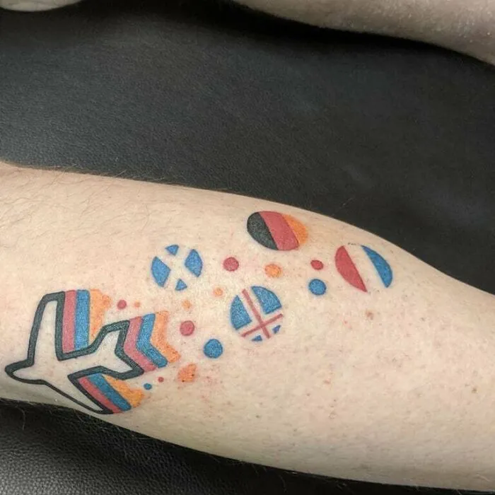 Lower leg tattoo with colorful airplane and flag designs.