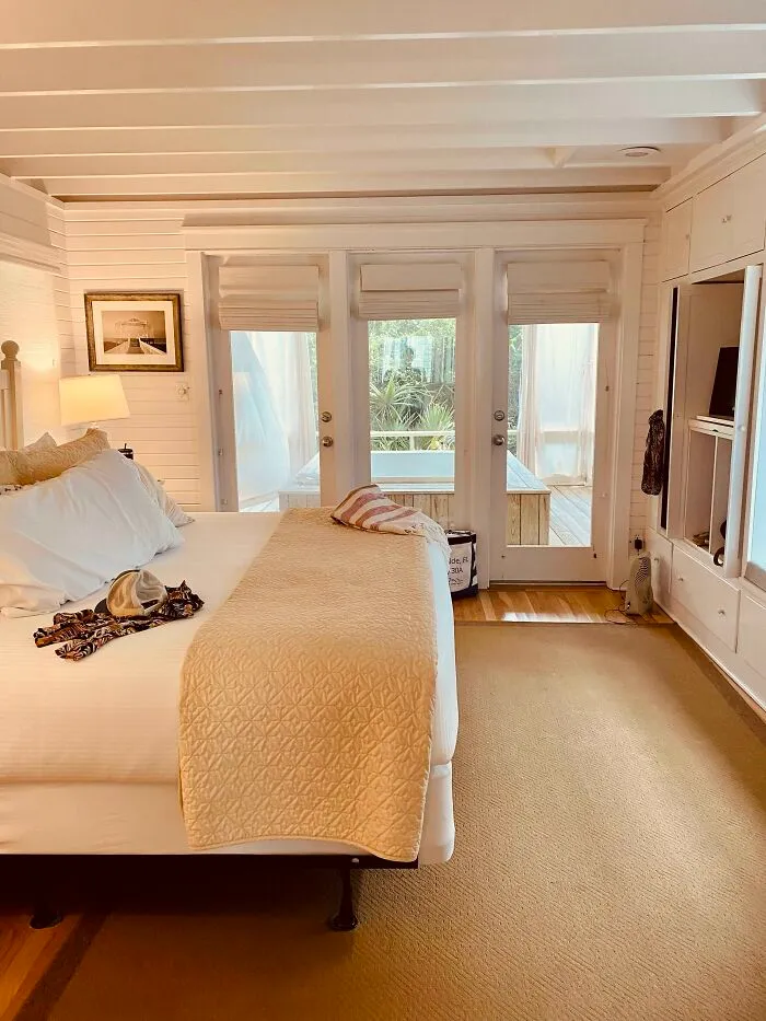 Cozy bedroom with white walls, large windows, and a plush bed, showcasing stylish home decoration.