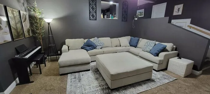 Cozy living room with a beige sectional sofa, blue cushions, and a piano, showcasing stylish home decoration ideas.