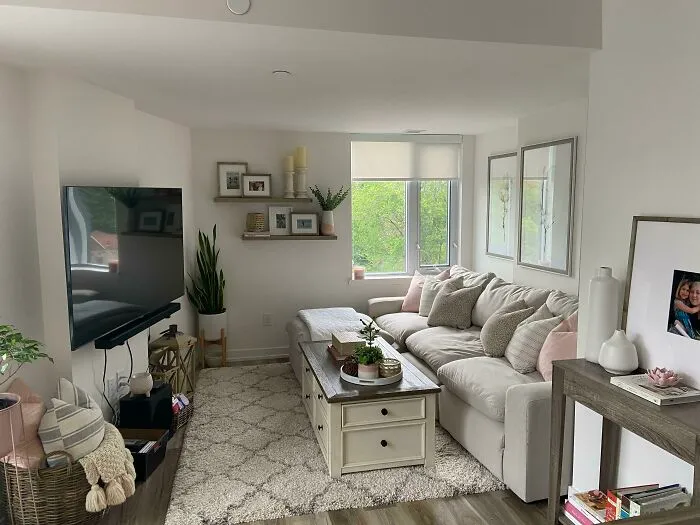 Home decoration ideas with a cozy living room, white sofa, soft pillows, and wooden shelves, creating a serene atmosphere.