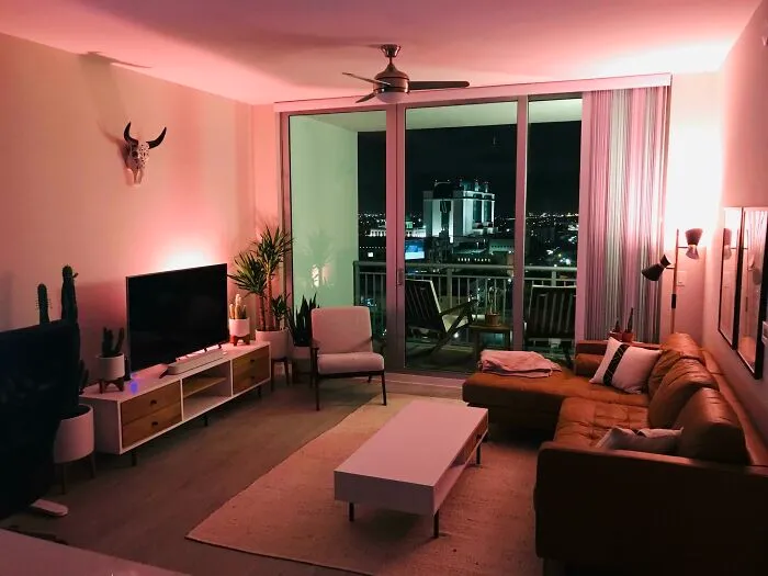 Cozy living room with modern home decoration, featuring a leather sofa and balcony view at night.