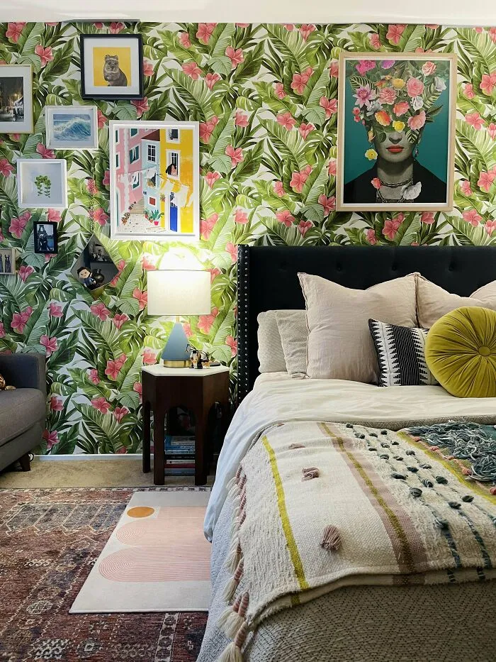 Bedroom with floral wallpaper and eclectic decor, featuring framed art and a cozy bed setup, enhancing home decoration ideas.