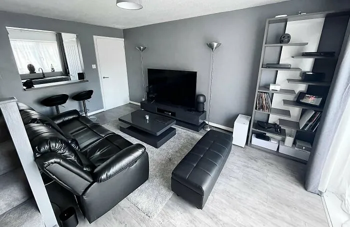 Modern living room with black leather furniture and a sleek entertainment setup, showcasing stylish home decoration ideas.
