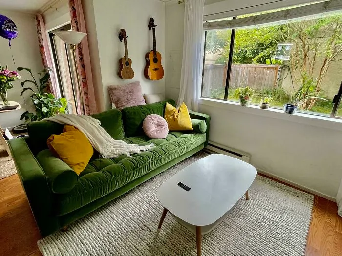 Cozy living room with green couch, colorful pillows, and guitars on the wall; home decoration inspiration.