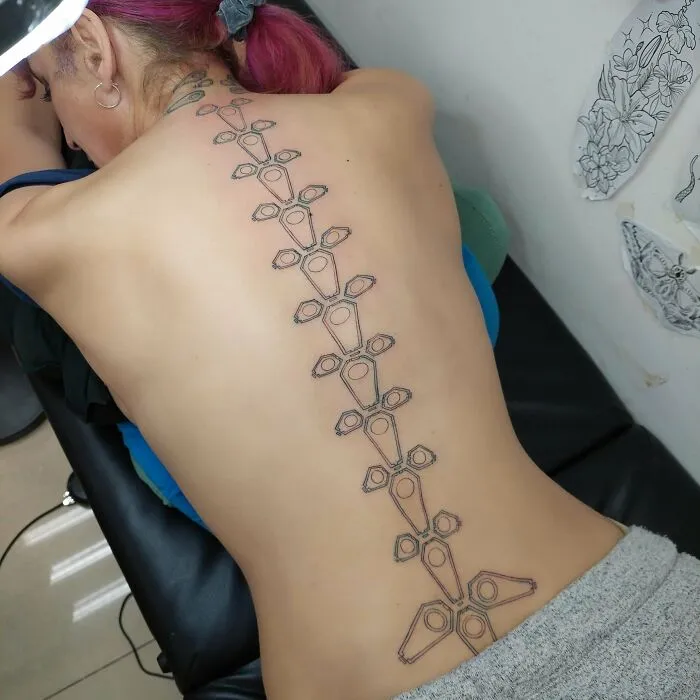 A unique spine tattoo design covering a woman's back, showcasing detailed geometric patterns.