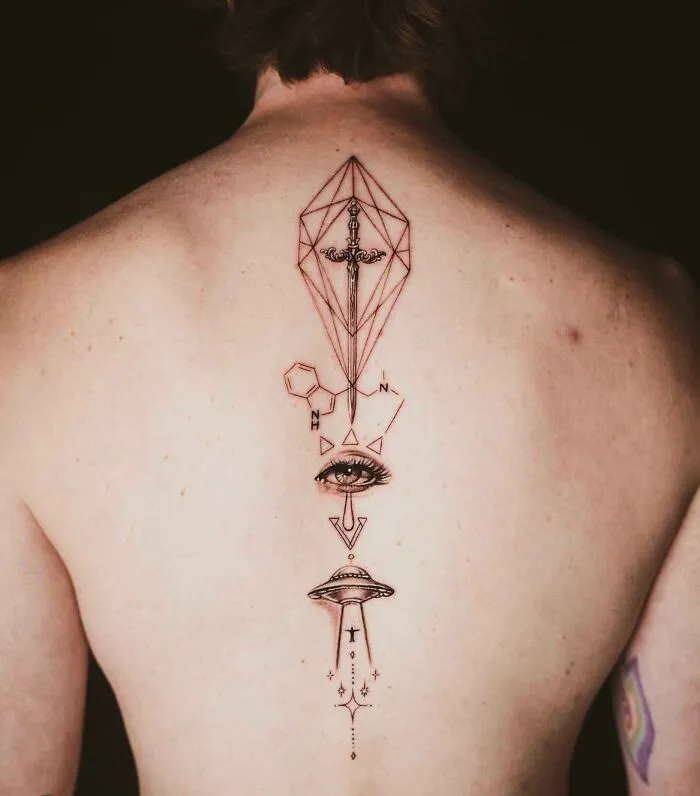 Elegant spine tattoo with geometric and surreal elements featuring a sword, eye, and UFO on a person's back.