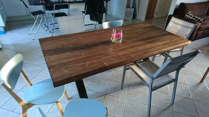 Wooden dining table with modern chairs, decorated with a simple floral vase, showcasing home decoration ideas.