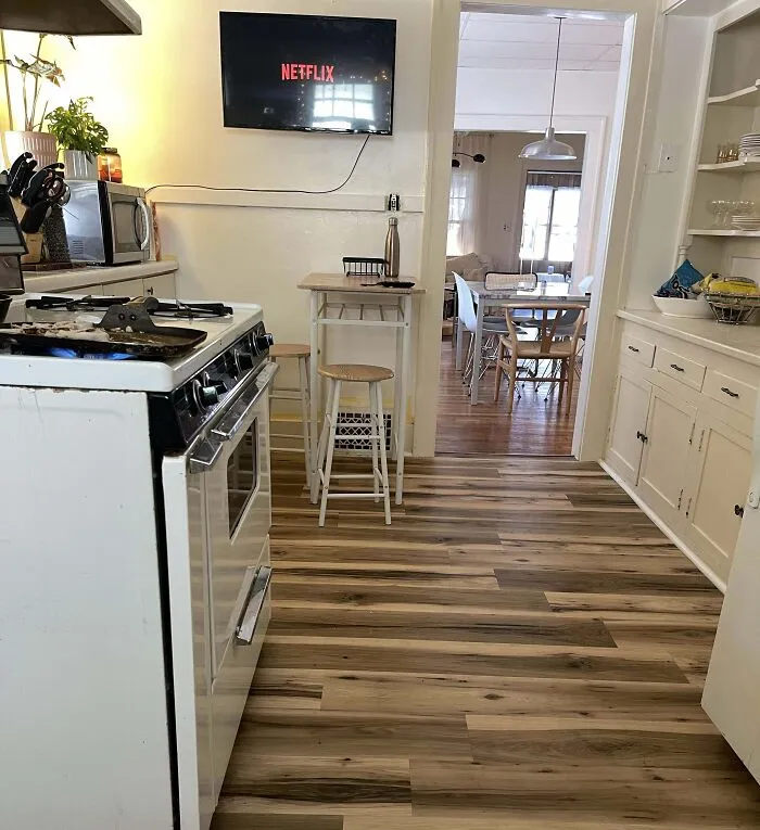 Small kitchen with wood flooring, white cabinets, and a wall-mounted TV for home decoration ideas.