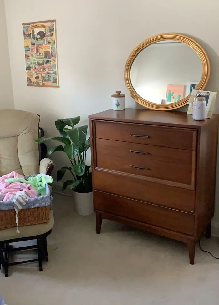 Cozy home decoration with a wooden dresser, round mirror, and a potted plant for a stylish living space.