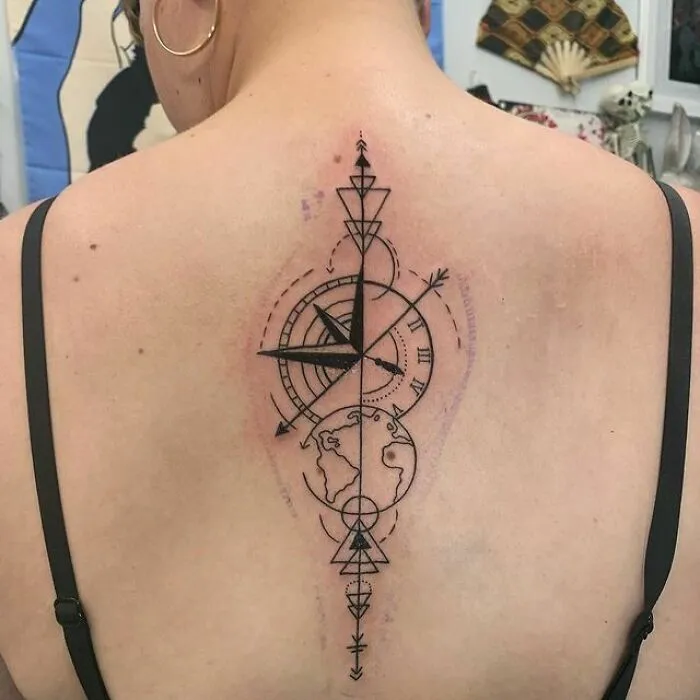 Geometric spine tattoo featuring a compass and globe design.