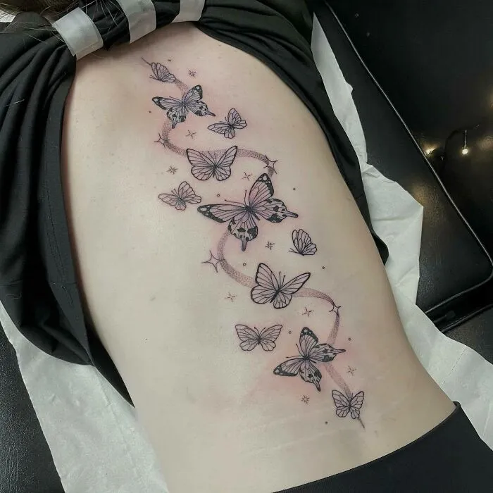 Elegant spine tattoo with butterfly design for men and women, showcasing intricate details along the back.