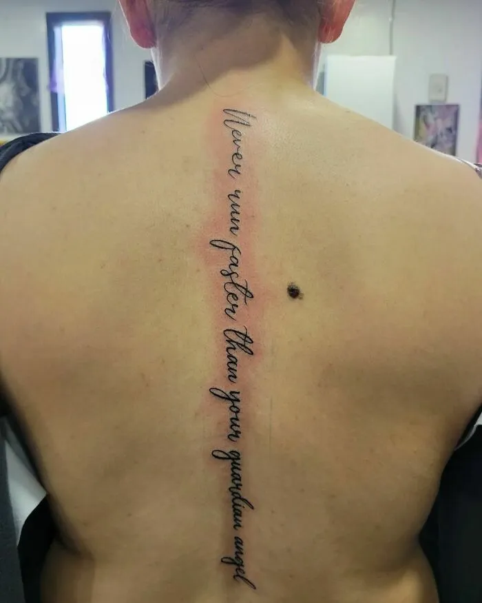Elegant script spine tattoo with meaningful quote.