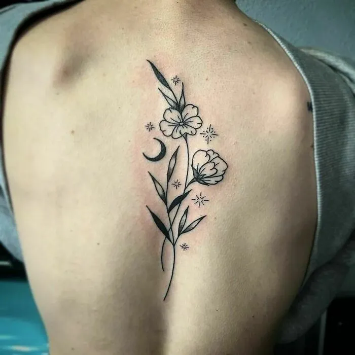 Elegant spine tattoo featuring floral design with stars and a crescent moon.