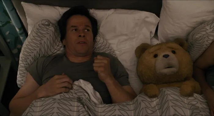 A man lying in bed next to a teddy bear, symbolizing iconic best friend duos in a cozy setting.