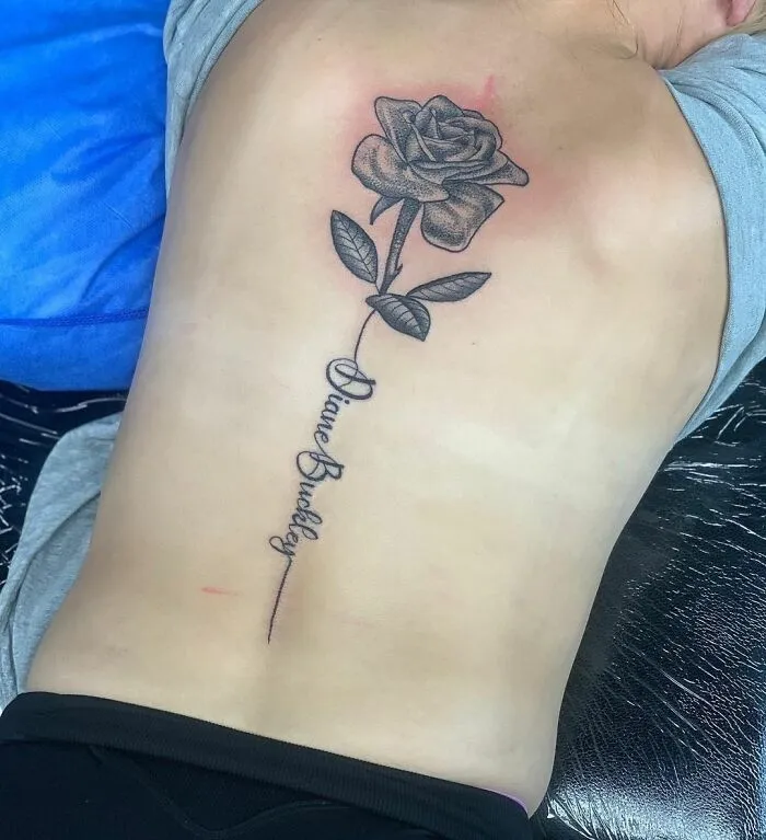 Elegant spine tattoo featuring a detailed rose design on a person's back.