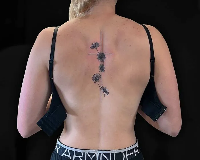Elegant spine tattoo featuring floral design on a woman's back.