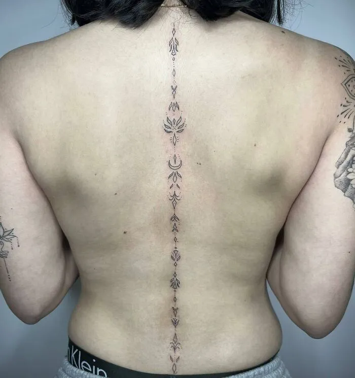Elegant spine tattoo featuring intricate design on a person's back.