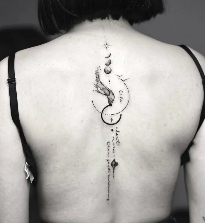 Elegant spine tattoo featuring celestial designs with stars and planets on a woman's back.