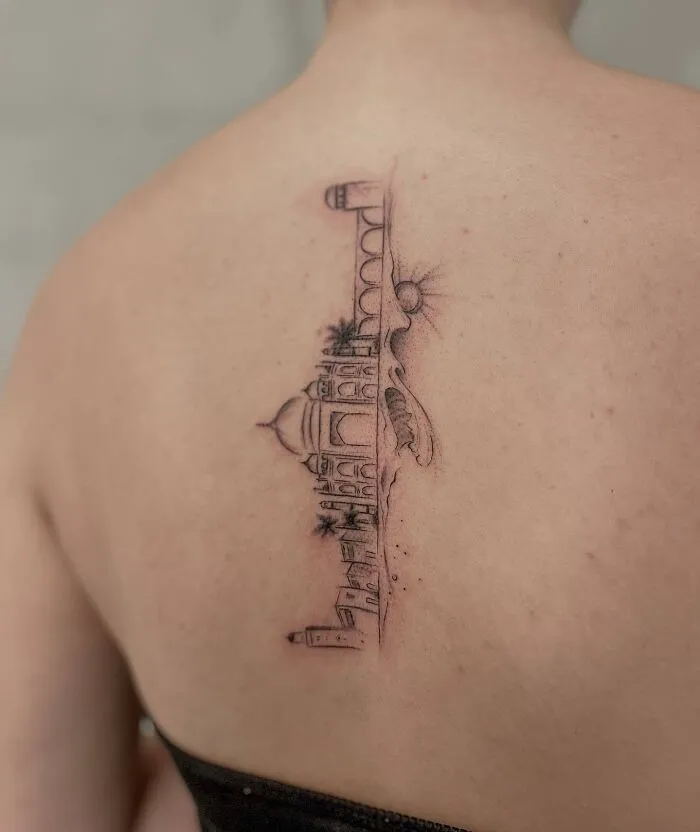 Elegant spine tattoo featuring a delicate architectural design on person's back.