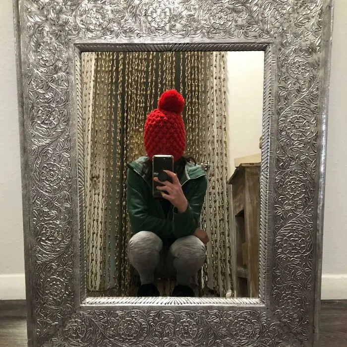 Woman taking a picture with a hat on her face 