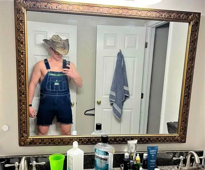 Man in an interesting outfit taking a picture of a mirror 