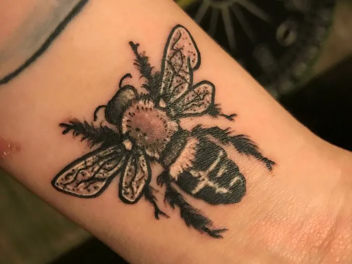 Detailed bee wrist tattoo design.