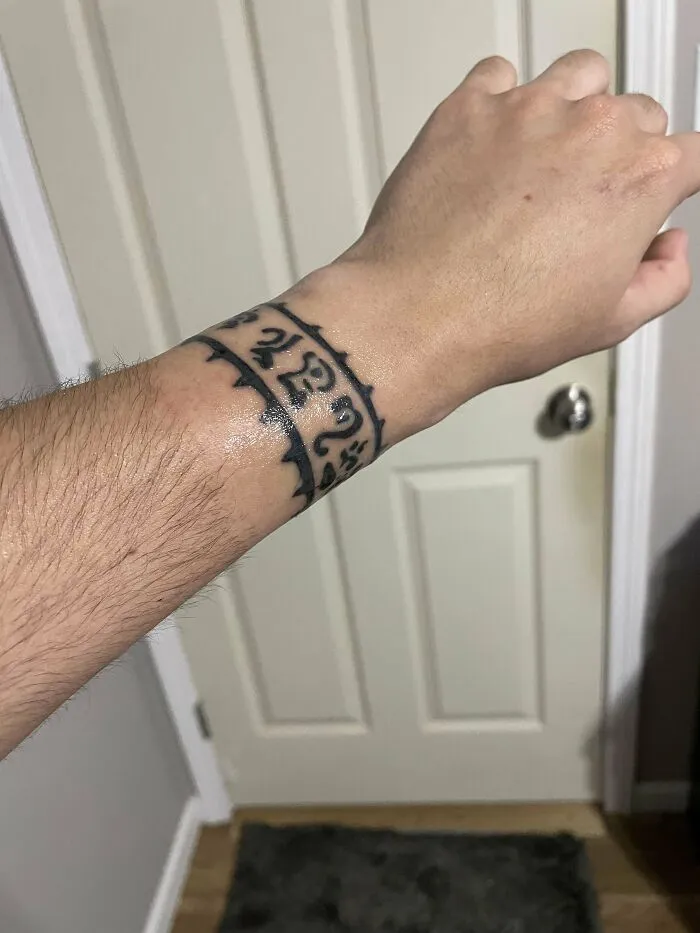 Wrist tattoo with a bold, black tribal band design, showcasing unique tattoo art style.