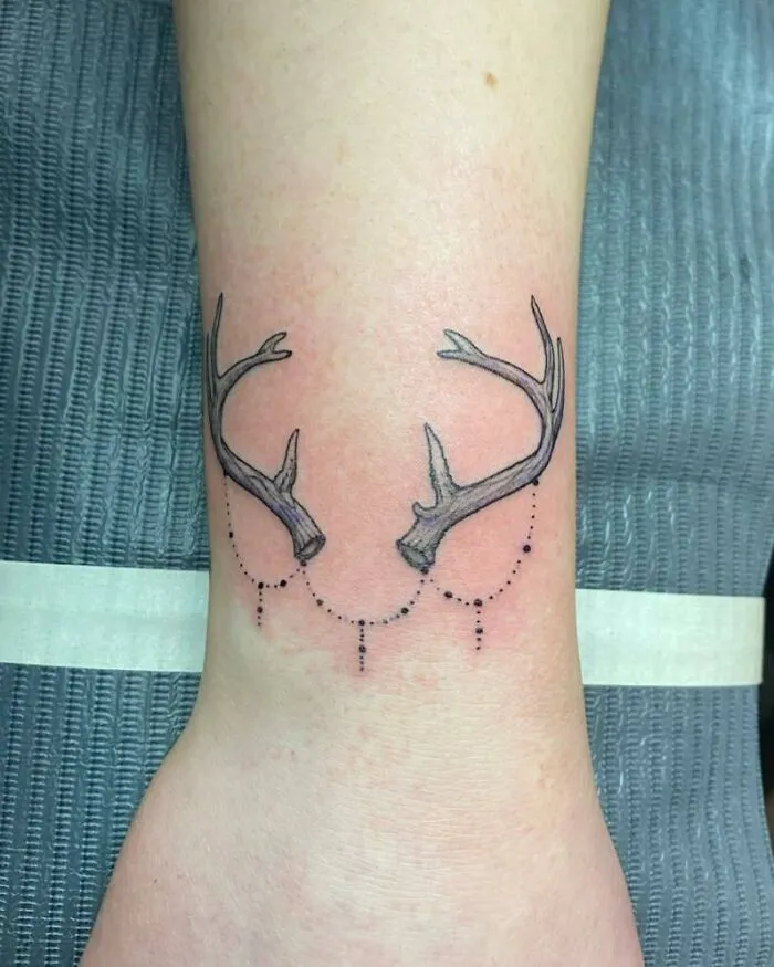 Antler wrist tattoo design with dotted chains, showcasing creative tattoo artistry.