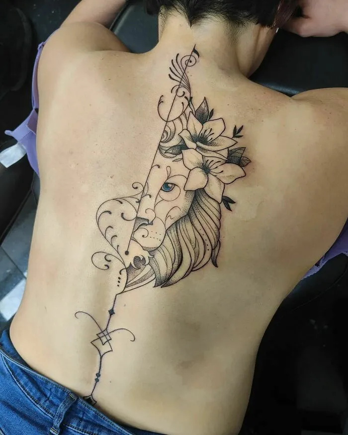 Elegant spine tattoo featuring a lion and floral design on a woman's back.