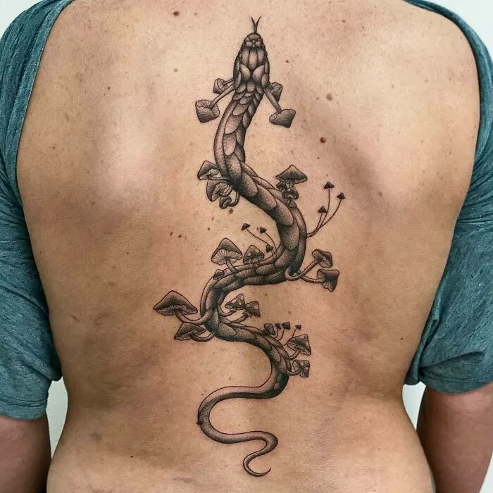 Intricate spine tattoo featuring a snake intertwined with mushrooms on a person's back.