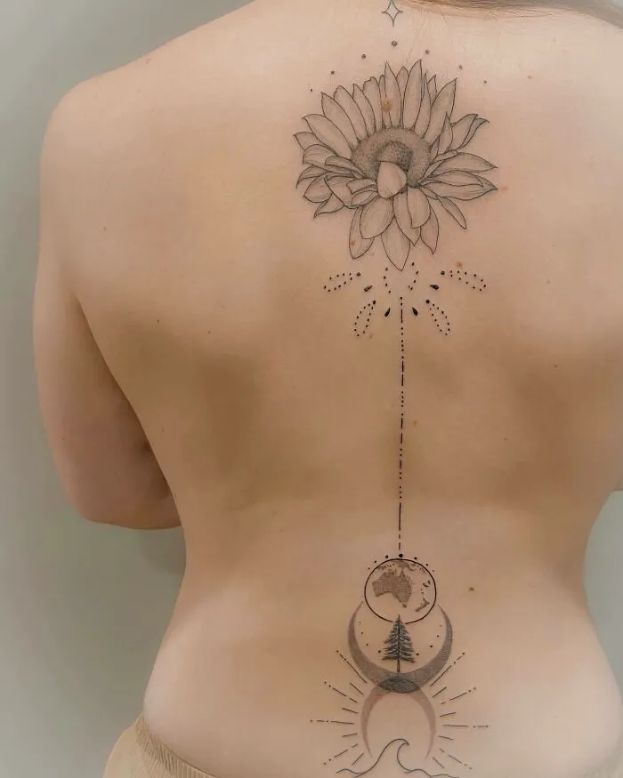 Elegant spine tattoo featuring floral and lunar designs along a woman's back.