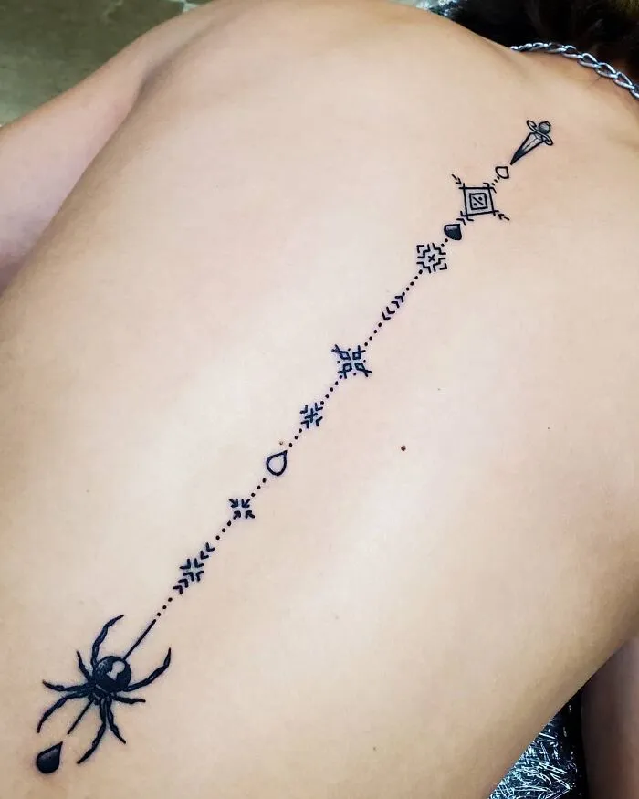 Elegant spine tattoo featuring geometric designs and a spider motif along the backbone.